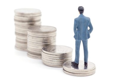 Miniature businessman and coins on white background